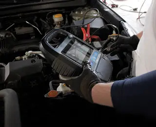 A Les Schwab technician inspecting a vehicle's battery