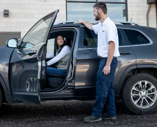 Les Schwab Employee greeting a customer at her car.