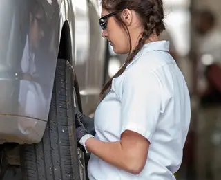 Les Schwab employee rotating tires on a passenger car