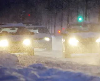 Headlights shining on a snowy winter road.