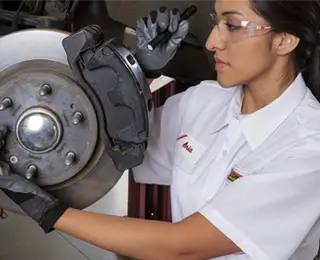 A Les Schwab technician completing a brake check on a brake assembly.