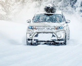 CUV with a cargo carrier driving through snow.